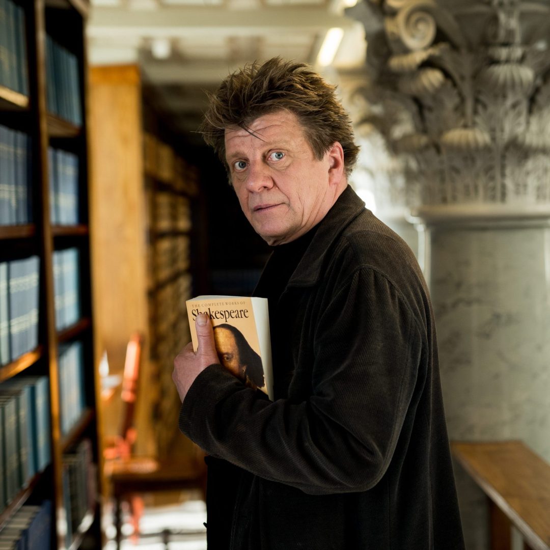 Näyttelijä Timo Torikka Kansalliskirjastossa kirja kainalossa.