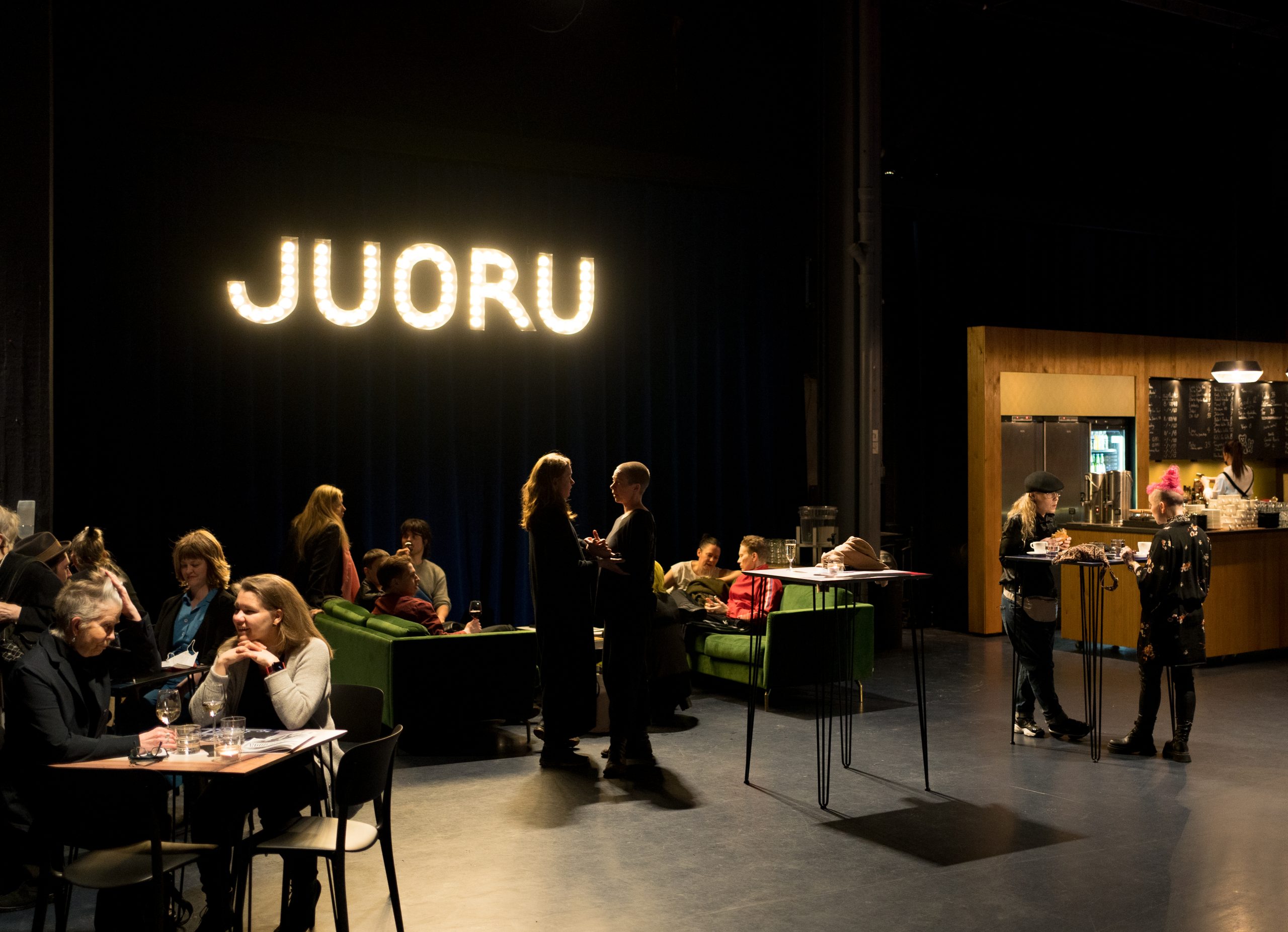 Teatterin baari, jossa asiakkaat seisovat ja istuvat.