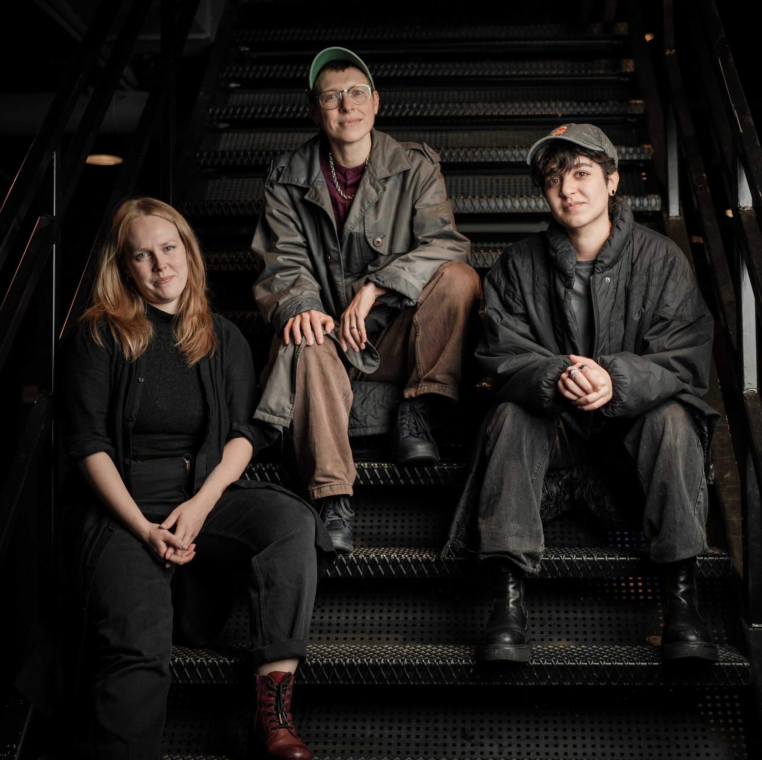 Martta Pesonen, Homa Shokri ja Dash Che istuvat rappusilla.