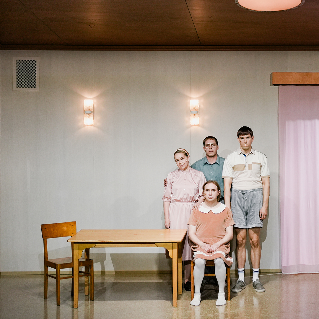Teatterin näyttämöllä neljä näyttelijää perhepotretissa.