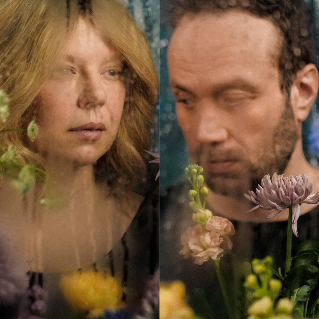 Markkinointikuva: Huurteinen ikkuna, kukkia ja kaksi ihmistä.