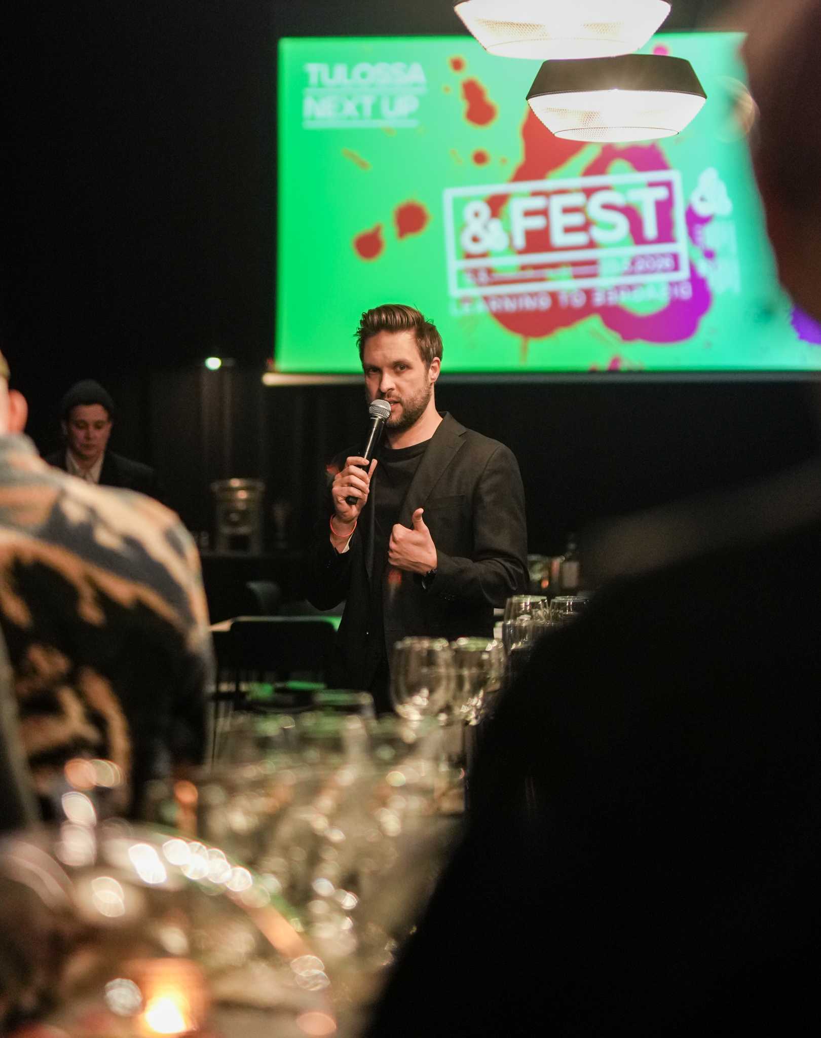 Jussi Sorjanen puhuu mikrofoniin. Taustalla &Fest-kuva.