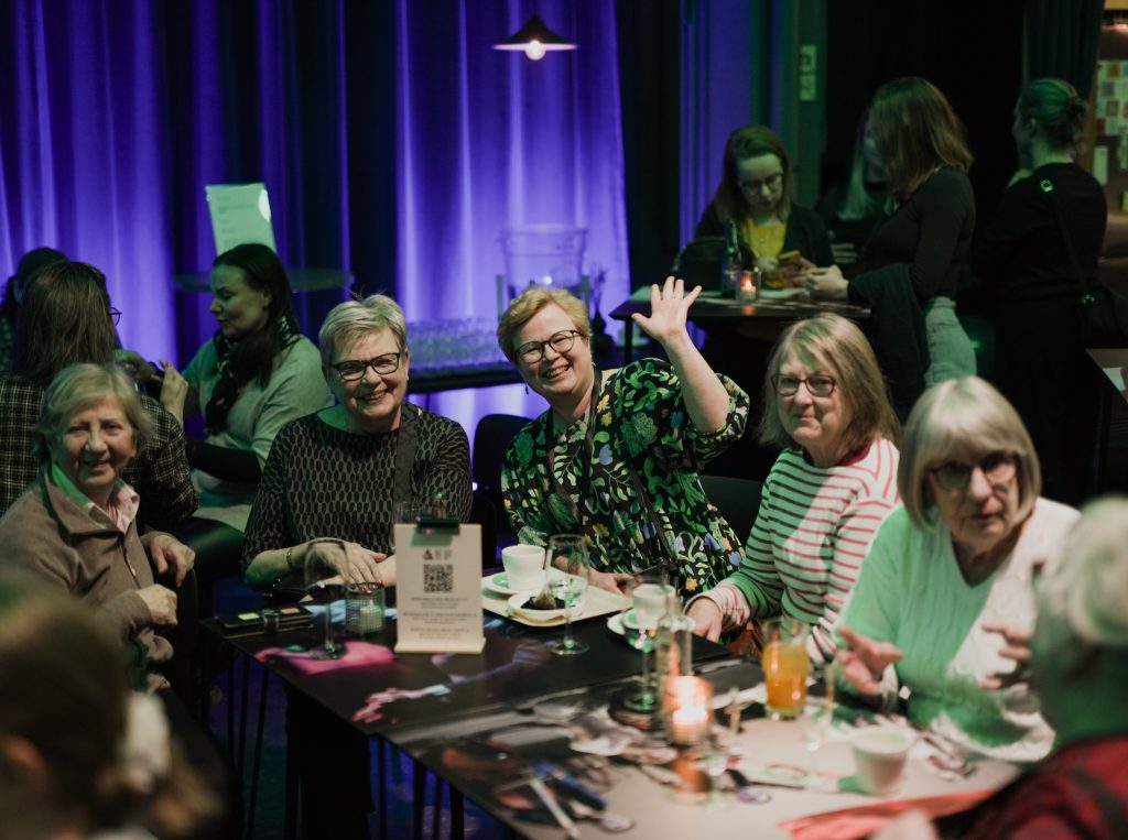 Ryhmä ihmisiä istuu pöydän ääressä.