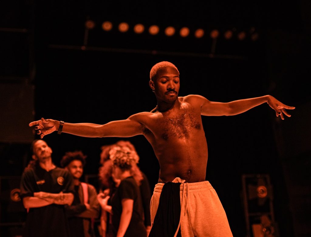 Esiintyjä levittää käsivarsiaan näyttämöllä.