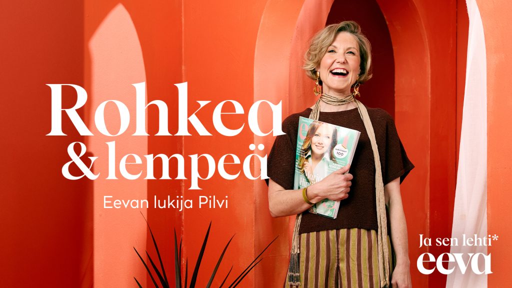 Hymyilevä aikuinen nainen pitää kädessään Eeva-lehteä. Teksti Rohkea & lempeä. Eevan lukija Pilvi. Ja sen lehti Eeva.