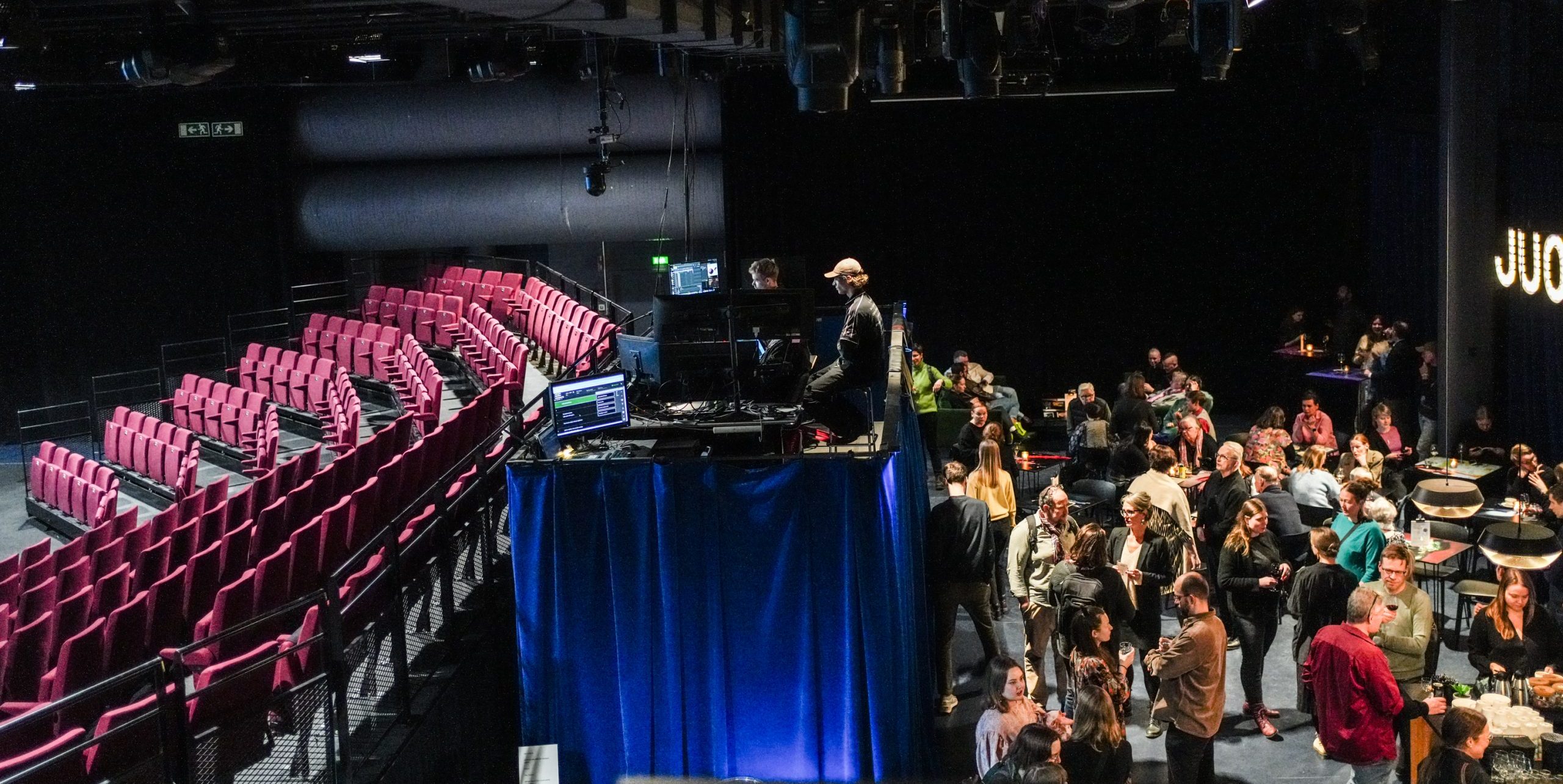 Teatterisali ylhäältä päin: vasemmalla katsomo penkkeineen, oikealla yleisölämpiö, jossa yleisöä seurustelemassa, keskellä tarkkaamo.